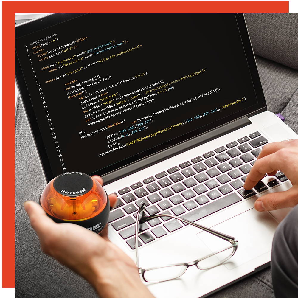 Hand holding an NSD Spinner beside a laptop with code on the screen