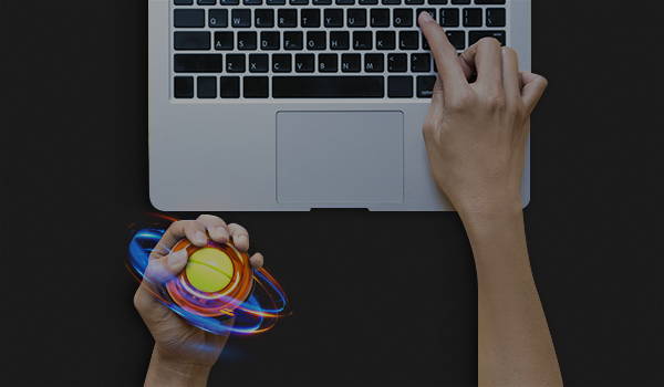 Hand holding an NSD Spinner next to a laptop keyboard