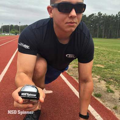 Athlete crouching on a running track while holding an NSD Spinner