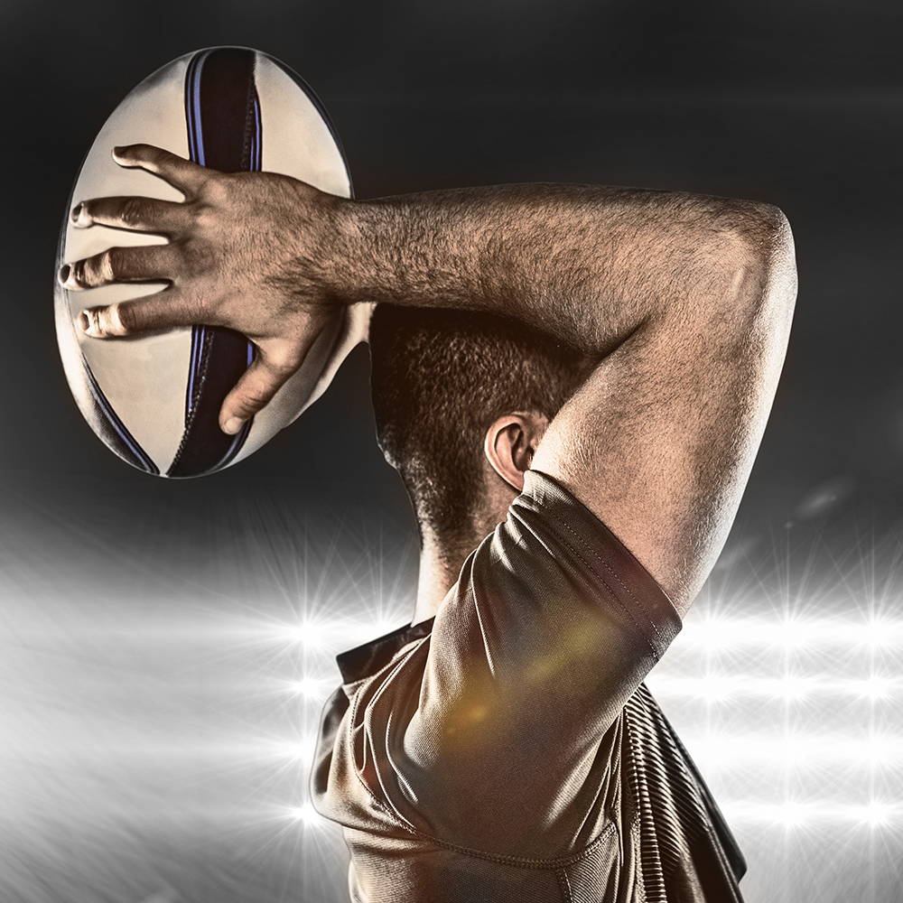 Rugby player holding a rugby ball behind his head
